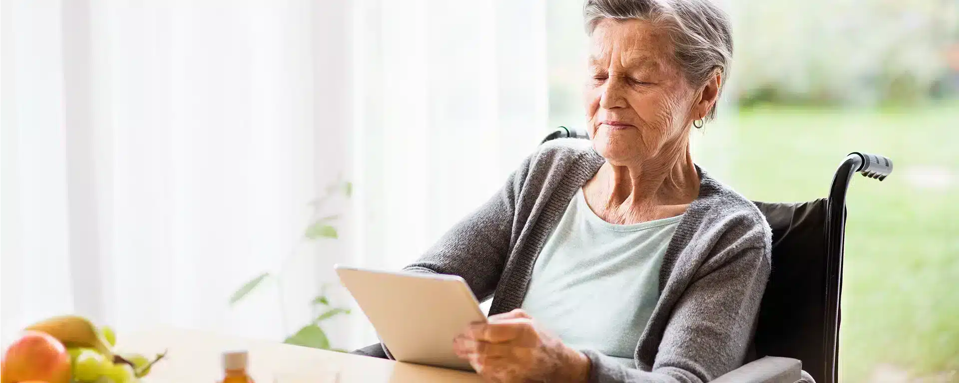 A senior woman reading on an electronic tablet.